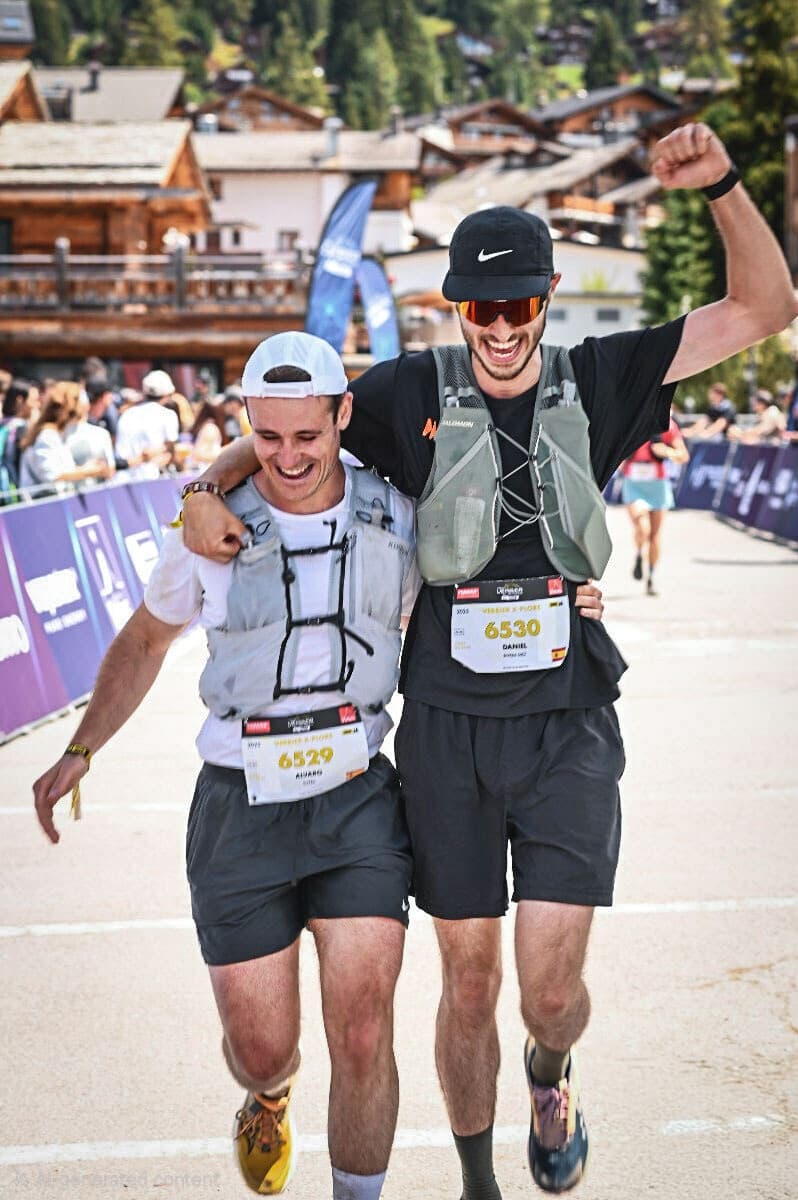 Two trail runners celebrating together at a mountain race finish line